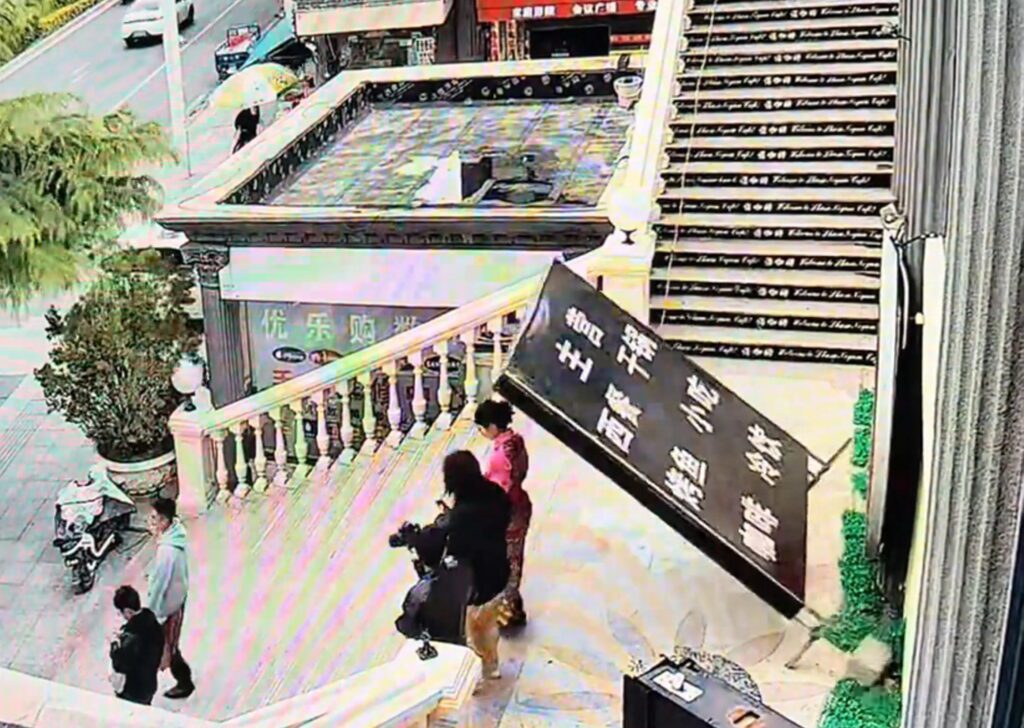 Woman knocked down stairs by falling advertising sign - Discover SWNS